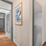Heller Wohnungsflur mit grauen Innentüren und Boden in Fischgrätoptik