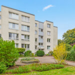 Mehrfamilienhaus mit hellem Fassadenanstrich und begrüntem Eingangsbereich