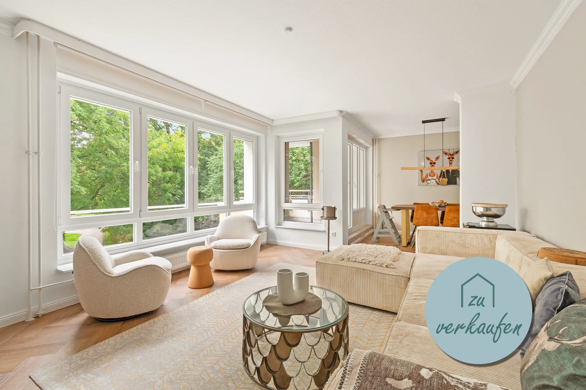 Helles Wohnzimmer mit großer Fensterfront, Sitzbereich und Parkblick