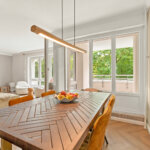 Heller Essbereich mit großem Holztisch und Glastür zum Westbalkon
