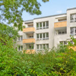 Rückseite des Mehrfamilienhauses mit Balkonen und dichter Begrünung