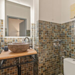 Separates Gäste-WC mit Mosaikfliesen, Aufsatzwaschbecken und Spiegel